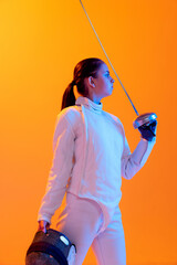 Studio shot of professional fencer in white fencing costume and mask in action, motion isolated on...