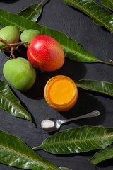 Top view shot of a mango jam near the mangos and mango tree leaves