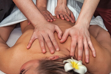 Massage in four hands in SPA salon. Two massaging therapist makes massage back for woman