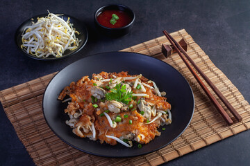 Hot pan of crispy fried oyster omelette served with bean sprout and spicy sauce.