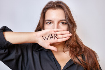A beautiful girl in a black shirt covers her mouth with her hand with the inscription "war"
