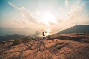 Rear view of a man standing on the edge of a mountain top overlooking the coast of Hong Kong