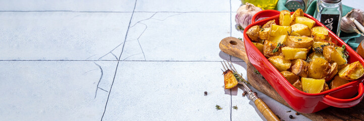 Slices of fried or baked potato wedges with herbs and spices in frying pan copy space