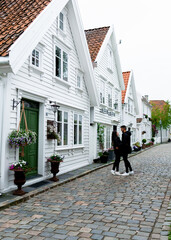 Young tourist couple in a street known for its typical Scandinavian white houses in Stavanger, Norway.