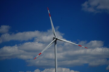 Windmill blades with red lines against a blue sky with clouds close-up