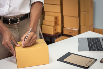 Small business owner packing in the cardbox at workplace. Cropped shot of man preparing a parcel for delivery at online selling business office. Ecommerce drop shipping shipment service concept.