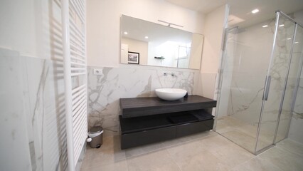 Spacious bathroom in gray tones with heated floors, walk-in shower and sink vanity. Modern bathroom...