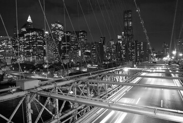 Grayscale view from the Brooklyn bridge to the skyscrapers illuminated with the lights