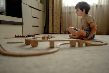 a boy at home in a room is building a railway, a child is playing with a toy train. Educational...