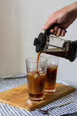 Tall highball glass while preparing cold bumble coffee on a wooden board. Step 4 Add coffee by carefully pouring it into the glass 