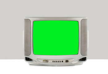 Silver analog old TV with green screen isolated on white table and gray background, clipping path