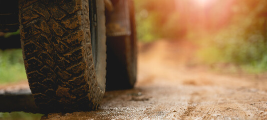 Part of an off-road vehicle on a dirt road with warm light. Adventure concept.Tire off-road on mud © PIPAT