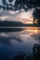 Fototapeta premium Serene view of a lake during sundown captured using long exposure with perfect reflection
