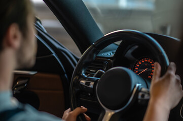 Young auto repair shop worker sitting in a car salon for car inspection