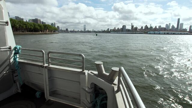Sailing by the NYC ferry. View of high cargo cranes, skyscrapers of Manhattan. Approaching the Gouverneur island, beautiful green coastline and nice houses. Sumer day. USA