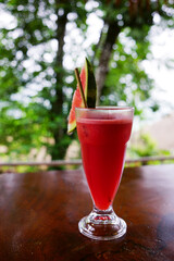 Refreshing watermelon juice with slice decoration in summer garden background.                                