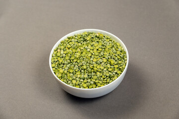 Uncooked food. Dry split peas in a white ceramic bowl. Green beans. Gray background. View from above at an angle. Selective focus.