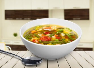 Tasty clear soup with beef slices and vegetables. Served in bowl on desk