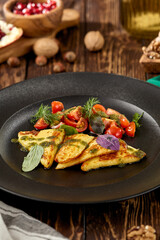 Grilled halloumi cheese with pesto sauce and tomatoes on black plate. Appetizer from fried cheese in greek style on wooden background. Hot appetizer of halloumi cheese in rustic style.