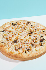 Italian pizza with mushrooms and creamy sauce on coloured background. Mushroom pizza with cheese in minimal style on light blue color. American pizza delivery concept with color backdrop