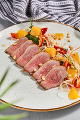 Healthy salad with duck meat, orange and vegetables. Chinese food - duck salad with citrus and fresh dressing. Sliced duck meat with crispy vegetables and pine nuts.