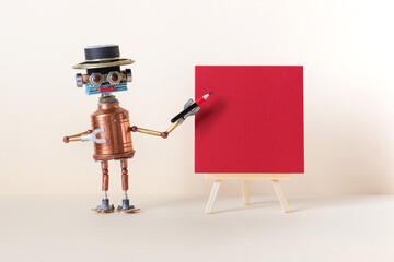 A robot artist poses with a pencil next to a wooden easel, red color paper poster. Gallery frame invitation card concept, empty frame mockup, copy space