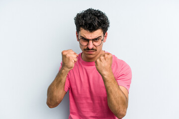 Young caucasian man isolated on blue background showing fist to camera, aggressive facial...