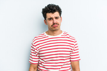 Young caucasian man isolated on blue background sad, serious face, feeling miserable and displeased.