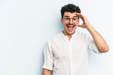 Young caucasian man isolated on blue background shouts loud, keeps eyes opened and hands tense.