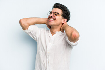 Young caucasian man isolated on blue background feeling confident, with hands behind the head.