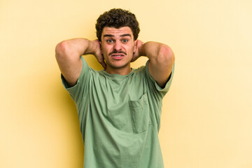 Young caucasian man isolated on yellow background screaming with rage.