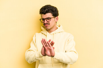 Young caucasian man isolated on yellow background doing a denial gesture