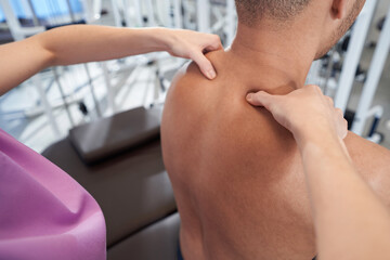 Female physiotherapist hands massaging male shoulders in clinic