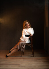Naklejka premium a girl in a white blouse, skirt and black shoes sits on a chair