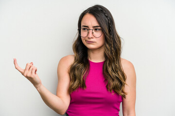 Young caucasian woman isolated on white background pointing with finger at you as if inviting come closer.