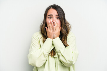 Young caucasian woman isolated on white background covering mouth with hands looking worried.