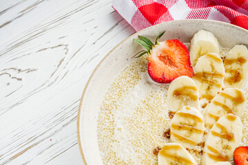 sweet porridge with quinoa and banana on a white rustic wooden background