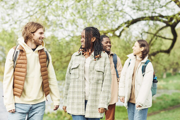 Group of multiethnic friends smiling and talking to each other during their walking in park