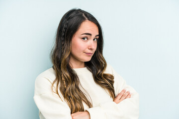 Young caucasian woman isolated on blue background suspicious, uncertain, examining you.