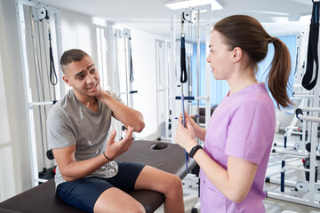Fototapeta premium African American man talking with doctor in physical therapy clinic