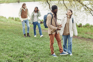 Two young multiethnic couple enjoying each other during their walk along the pond in the park