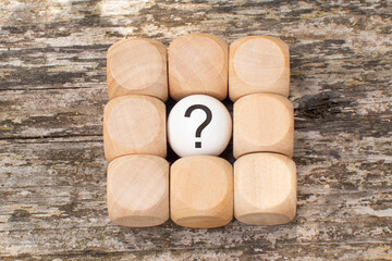 A question mark on a wooden table. FAQ frequency asked questions, answer and Brainstorming Concepts.