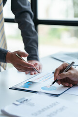 Group of business people meeting, discussing, analyzing graphs, financial data, and planning a marketing project together