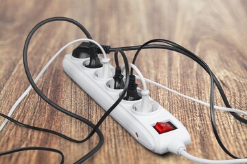 Unplugged electric appliance plug over switched off white power strip on the floor. Increasing the energy costs, heating costs, save electricity concepts.