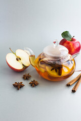 Tea with apple, cinnamon and anise in the glass teapot on the gray  background. Location vertical.
