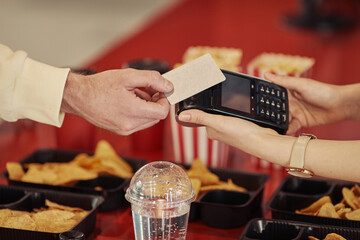Close-up of buyer paying with credit card for his popcorn with seller reaching terminal to him
