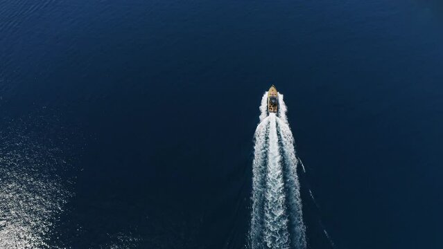 A luxury boat is approaching a bay with an abandoned shipwreck. A beautiful yellow approaches the bay on a turquoise water. A shipwreck on a sandy closed beach.