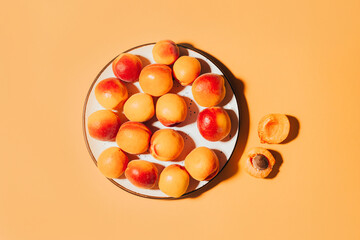 top view of apricots in round plate on orange background