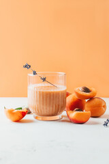 close-up on ripe apricots and apricot smoothie on peach background