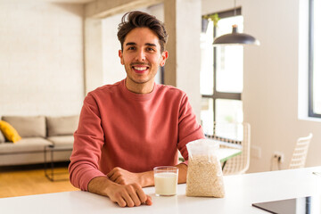 Fototapeta na wymiar Young mixed race man eating oatmeal and milk for breakfast in his kitchen